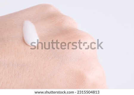 White moisturizer drop of essence, serum or cream on the extra dry skin, close up. Macro photo of woman's hand with cream drop on white background. Royalty-Free Stock Photo #2315504813