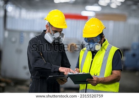 Two officers wearing gas masks, holding tablet and book, inspect the chemical spill site in an industrial warehouse to assess the damage, wearing gas masks, inspecting and evaluating toxicity of leak. Royalty-Free Stock Photo #2315520759