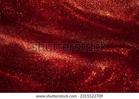 Magic Galaxy of golden dust particles in red fluid. Various stains and overflows of gold particles with burgundy tints. Fantastically beautiful abstract background.