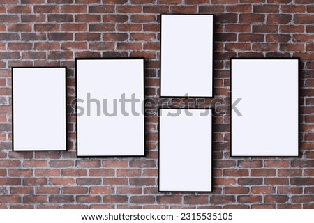 Mock-ups of 5 vertical black frames for pictures with a white blank copy space for text or design on a red brick wall baclground