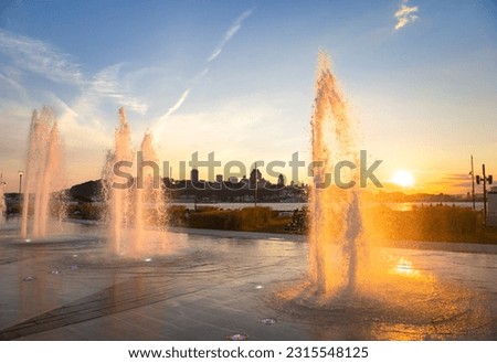 Water fountains backlit by an orange sunset Royalty-Free Stock Photo #2315548125