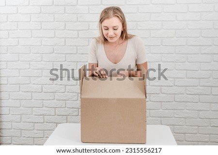 Pretty woman with open cardboard box. Delivering a parcel
