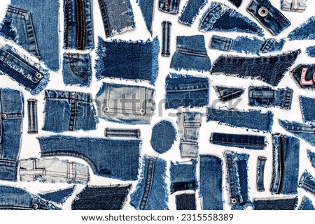 Destroyed torn denim blue jeans fabric pieces on white background, flat lay. Recycle old jeans denim concept. Love Denim Jeans. Royalty-Free Stock Photo #2315558389