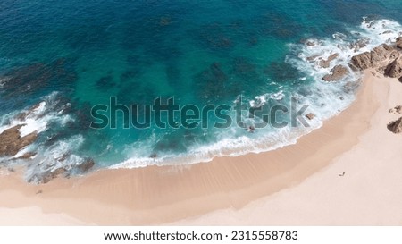 Aerial photo of one man walking on isolated and lonely Playa El Chileno beach, Baja California, Mexico. Drone picture of picturesque beach front with find sad and turquoise blue sea water in summer.
