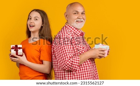 happy amazed teen girl and grandfather with present box for anniversary