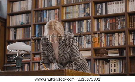 Female researcher working with historical archives in a library late at night Royalty-Free Stock Photo #2315575001