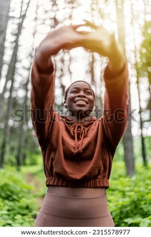 Morning workout. Young attractive multiracial woman in sportswear doing stretching hand before exercise in nature at sunrise. Healthy lifestyle concept