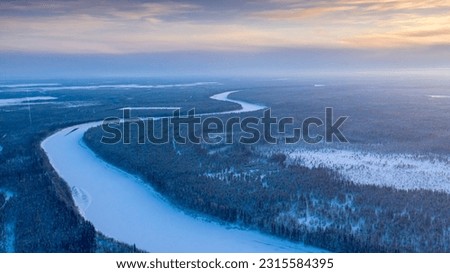Winding riverbed. Landscape of winter taiga. Russian winter of northern latitudes from a drone.