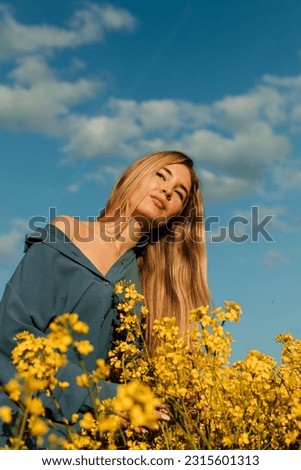 Beautiful woman standing in a rapeseed field.Rapeseed field against the blue sky