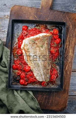 Traditional skinned backed skrei cod fish filet with tomato salsa ragu and herbs served as top view on a rustic metal sheet
