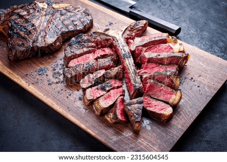 Modern style traditional barbecue dry aged wagyu porterhouse beef steak bistecca alla Fiorentina sliced and served as close-up on a wooden design board Royalty-Free Stock Photo #2315604545