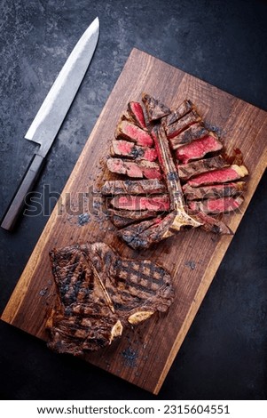 Modern style traditional barbecue dry aged wagyu porterhouse beef steak bistecca alla Fiorentina sliced and served as to view on a wooden design board  Royalty-Free Stock Photo #2315604551
