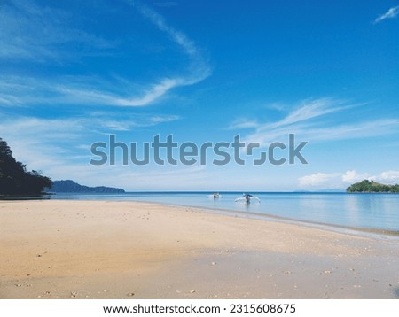 Beautiful beach with white sand, turquoise ocean, blue sky with clouds and palm tree over the water on a Sunny day. Perfect tropical landscape, Dunu Beach at North Gorontalo.