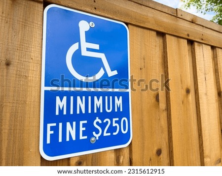 Blue ADA Handicapped sign on a wood fence.