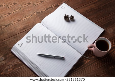 Notebook with pen and cup of coffee on wooden background