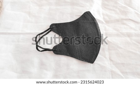 A surgical mask with a rubber earpiece. A typical 3-layer surgical mask covering the mouth and nose. Bacteria mask procedure. The concept of protection.