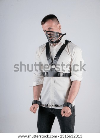 a white man with a short haircut and an athletic build in a shirt and a leather belt bdsm image on a light background