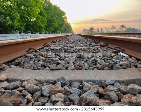 Jombang. Indonesia. Railroad track through the horizon with the background of the orange sky at sunrise. Picture taken using Frog Eye level technic.