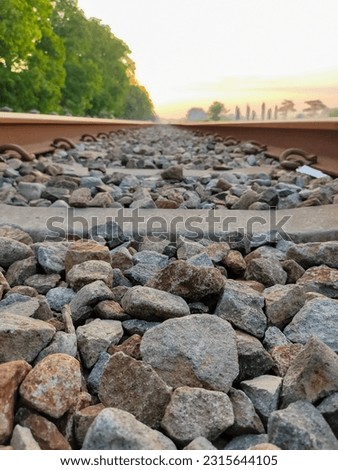 Jombang. Indonesia. Railroad track through the horizon with the background of the orange sky at sunrise. Picture taken using Frog Eye level technic.