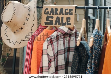Garage sale. Used clothes on floor hanger outdoors.