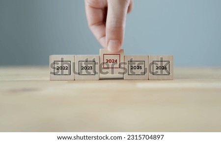 Focused on year 2024. Business planning and strategy in new year. Performance and highlight concept. Holding the wooden cubes with number 2024 on grey background. Start of year concept. 2024 banner.