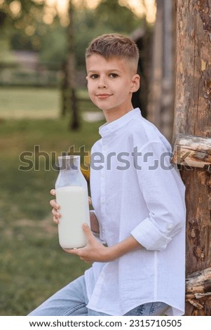 Portrait of a joyful boy on a farm drinking milk. Time relax. Talk and look away. Light sunny day. food and drink concept, healthy food. Little boy in a haystack drinking milk