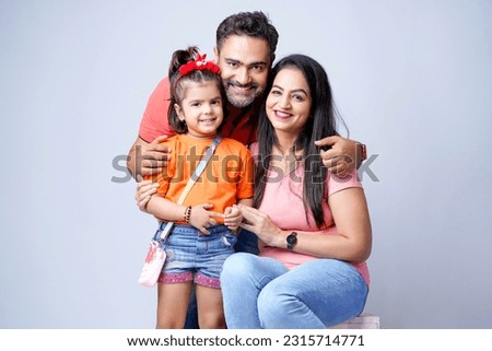 Indian happy family of a father, mother and daughter sitting together on a white background.