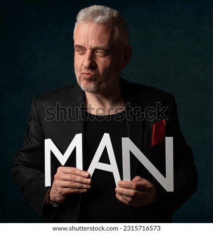 Man mature close headshot posing face still focused holding letter s making word MAN depicting himself to the letters. 