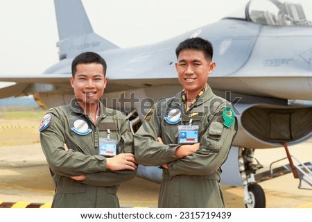 Portrait of men, fighter pilot team in military with jet and smile at airforce base with arms crossed in Korea. Freedom, transport and proud Asian soldier with airplane, confident and service in army Royalty-Free Stock Photo #2315719439