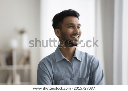 Happy successful handsome young Indian man casual indoor portrait. Positive confident professional, business man, entrepreneur in casual shirt looking at window away with toothy smile Royalty-Free Stock Photo #2315729097