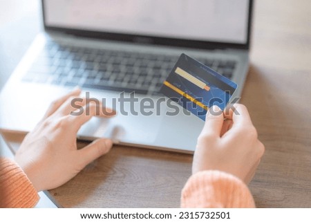 Woman holding credit card and working on laptop or notebook computer. Online shopping concept.