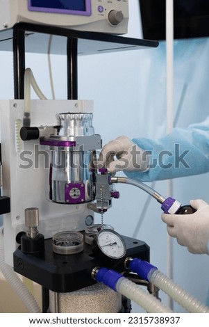 The hands of the anesthesiologist pour anesthesia from a bottle into an anesthetic gas apparatus. In the operating room, the anesthesiologist pours anesthesia into the apparatus. Royalty-Free Stock Photo #2315738937