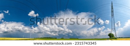  a thunderstorm moving across the countryside with wispy clouds in the sky and agricultural fields on the ground and overhead power lines or high-voltage power lines with electricity pylons and rotor 