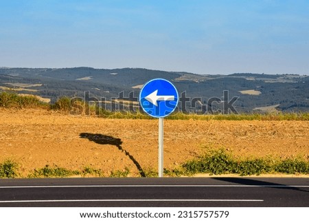 Blue traffic sign "Turn left" on the nature background