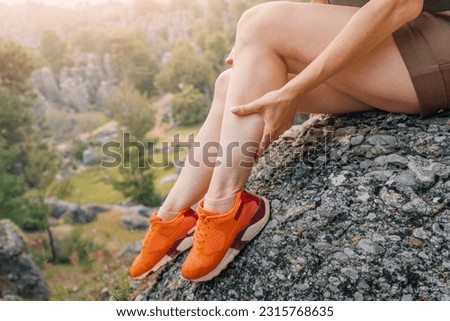 A girl massages the calf of her leg after an injury or stretching of a muscle during a hike Royalty-Free Stock Photo #2315768635