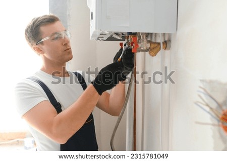 Professional plumber checking a boiler and pipes, boiler service concept. Royalty-Free Stock Photo #2315781049