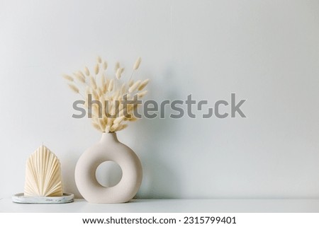 Dried hare's tail grass.Aesthetic cozy home decoration. Scandinavian minimal interior style. Hygge scene with candles. Creative composition of living room interior with copy space. Stylish round vase. Royalty-Free Stock Photo #2315799401