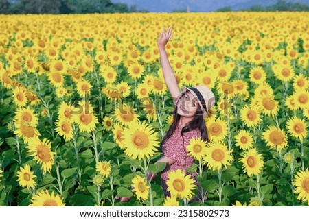 Beautiful young girl standing in the sunflowers field. Vacation time.
