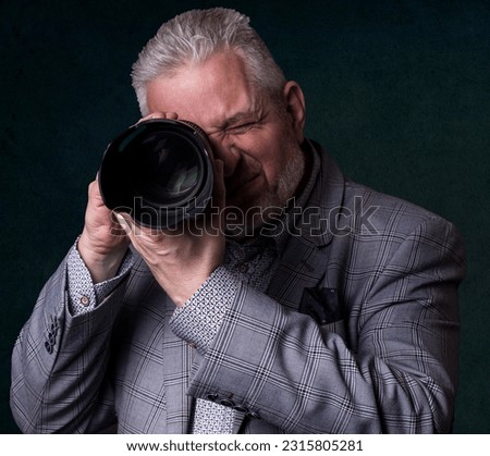 Man mature close headshot posing photographer holding photo equipment looking into camera holding lenses pointed at viewer