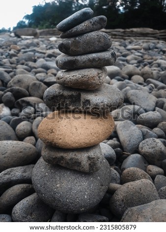 The balance stones are arranged in a pyramid shape, The balance stones with river stones in the background