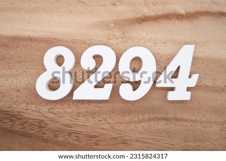 White number 8294 on a brown and light brown wooden background.