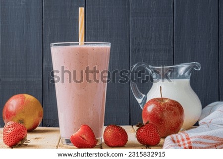 Fresh milkshake with strawberries. A glass of fresh strawberry milkshake, puree and fresh strawberries on a wooden background. Healthy food and drink concept