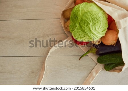 Vegetables and fruits falling out of tipped over bag next to large empty space over rustic wooden background