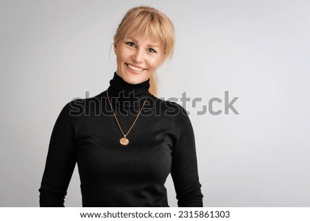 Cropped shot of blond haired woman wearing turtleneck sweater and cheerful smiling against isolated bacgkround. Copy space.