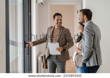 A young couple with a real-estate agent visiting an apartment for sale or for rent. Married couple buying an apartment. Real estate concept. Royalty-Free Stock Photo #2315892545