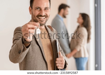 Portrait of a real estate agent in the apartment for sale or for rent.  A young married couple standing in the background. Real estate concept. Royalty-Free Stock Photo #2315892587