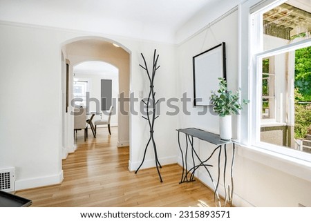 Front entry hall foyer with coat rack bench open door coat and hat on rack bright and sunny Royalty-Free Stock Photo #2315893571