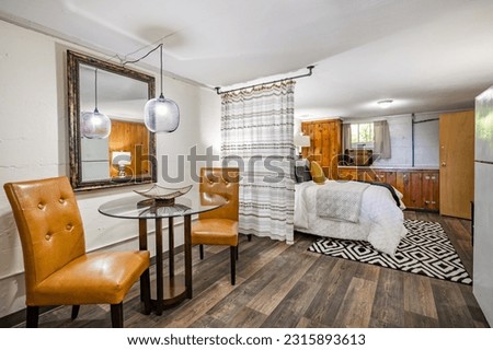 bedroom basement suite interior in older craftsman home with wooden cabinets staged bed curtain partition hanging on plumbing pipes from the ceiling  Royalty-Free Stock Photo #2315893613