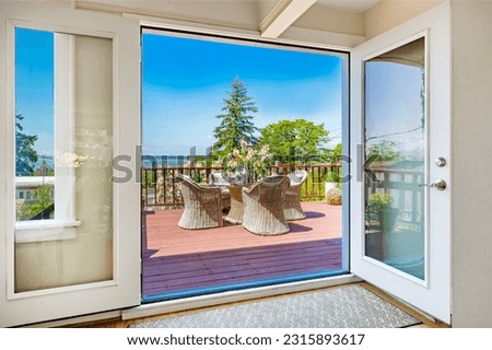 bright sunny patio deck with water view lake and ocean blue sky furnished with patio furniture chairs and table wicker seating