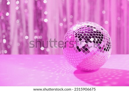 Shiny disco ball on table against blurred background, toned in pink. Space for text Royalty-Free Stock Photo #2315906675
